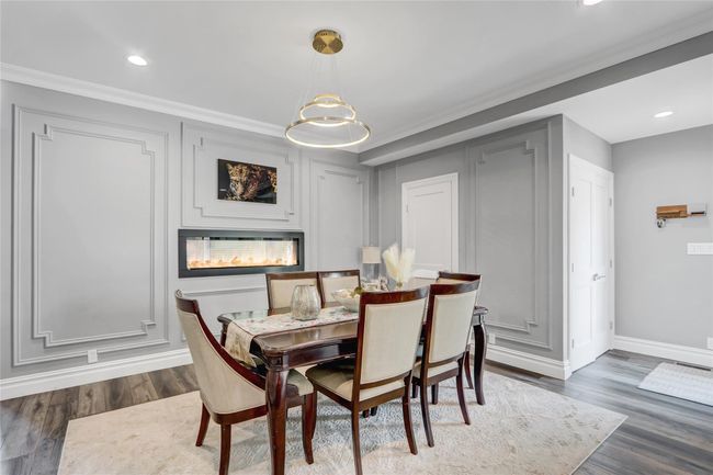 Dining area with baseboards, recessed lighting, dark wood-style floors, crown molding, and a glass covered fireplace | Image 6