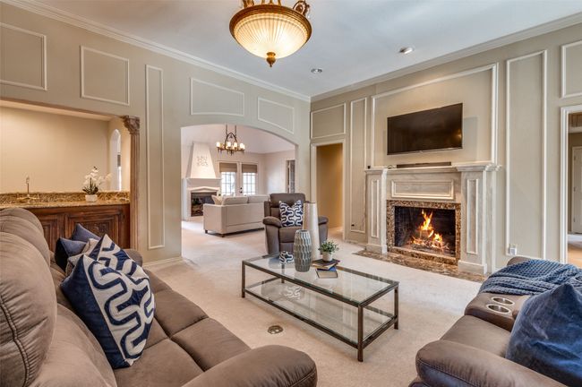 Carpeted living room featuring ornamental molding, arched walkways, a decorative wall, and a high end fireplace | Image 12