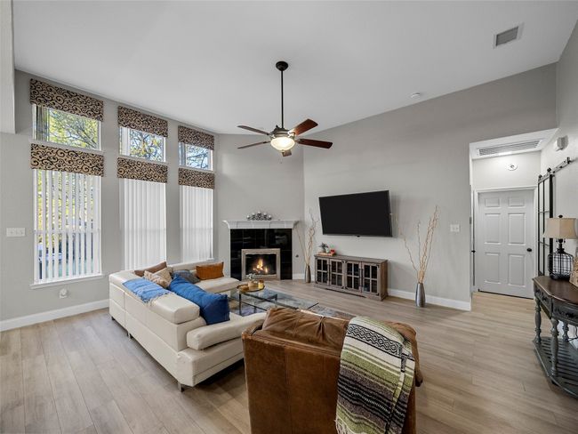 Living room with baseboards, a ceiling fan, wood finished floors, and visible vents | Image 14