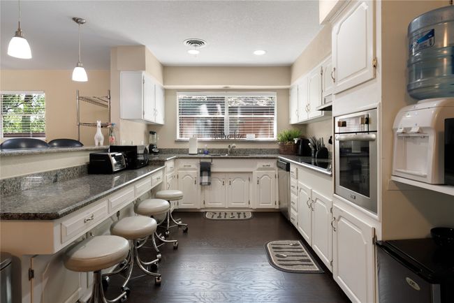Kitchen featuring appliances with stainless steel finishes, a peninsula, white cabinets, dark wood finished floors, and recessed lighting | Image 6