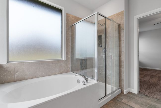 Bathroom with a bath, baseboards, wood finished floors, and a stall shower | Image 13