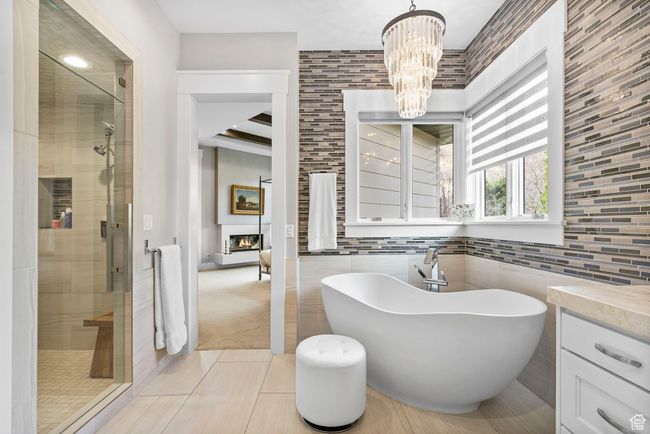 Full bath featuring tile patterned floors, a notable chandelier, a freestanding tub, and a stall shower | Image 39
