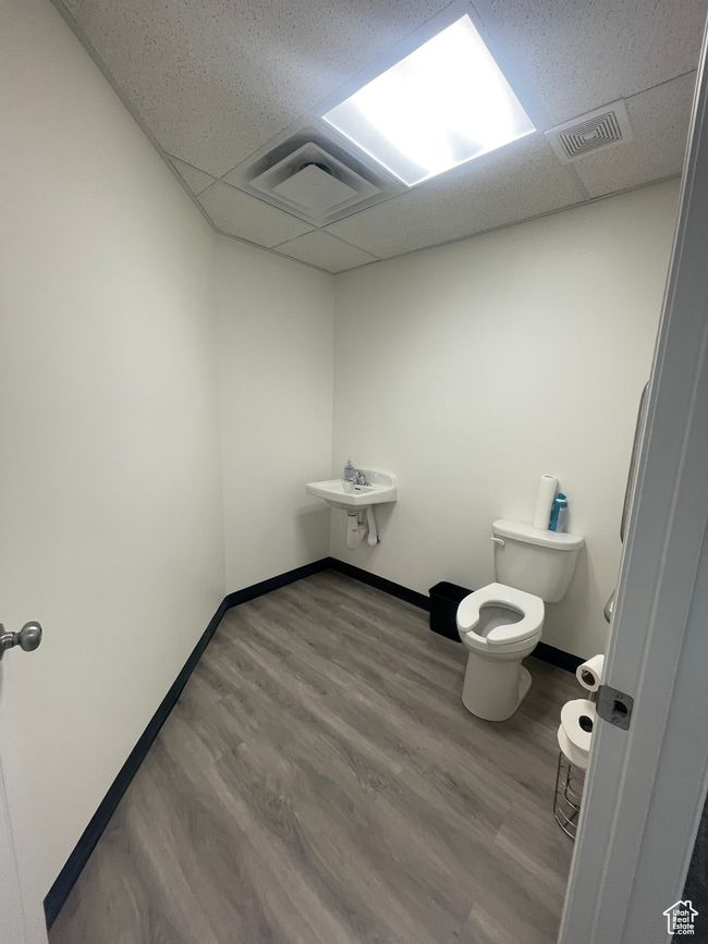 Bathroom with a drop ceiling, visible vents, toilet, and wood finished floors | Image 7