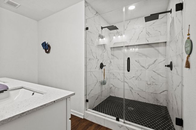 Bathroom featuring wood finished floors, vanity, a marble finish shower, and baseboards | Image 15