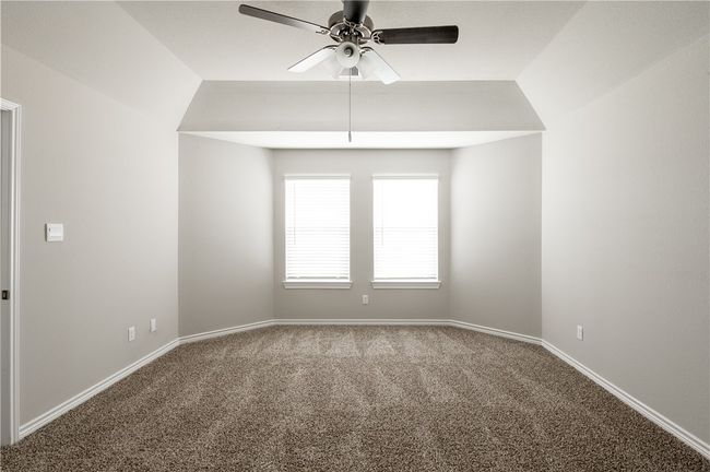 Carpeted empty room with lofted ceiling, a ceiling fan, and baseboards | Image 10