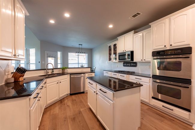 Kitchen featuring appliances with stainless steel finishes, recessed lighting, light wood finished floors, tasteful backsplash, and white cabinetry | Image 14
