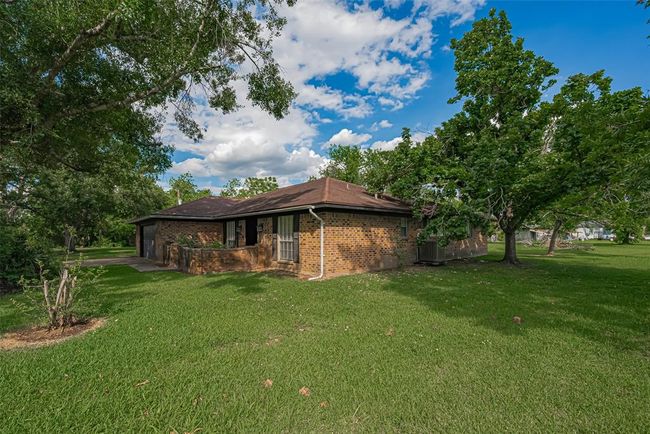 Charming single-story brick home with a spacious, lush green yard surrounded by mature trees. Ideal for outdoor relaxation and privacy. | Image 35