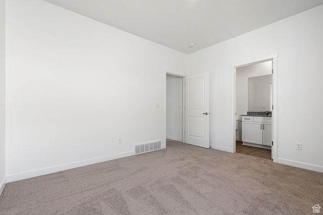 Unfurnished bedroom with ensuite bath, visible vents, baseboards, and carpet | Image 9
