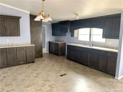 Kitchen with hanging light fixtures, sink, light tile patterned flooring, and ornamental molding | Image 3