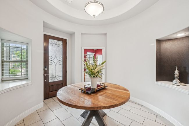 Grand Foyer with light tile patterned floors and tall baseboards, custom door with glass, decorative niches, and window to patio | Image 5