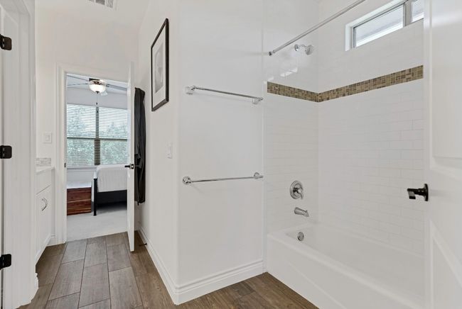 Ensuite bathroom featuring healthy amount of natural light, wood finished floors, shower / tub combination, and vanity | Image 22