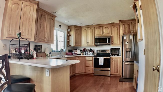 Kitchen featuring open shelves, light countertops, a peninsula, dark wood-style floors, and stainless steel appliances | Image 45
