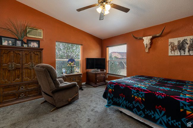 Carpeted bedroom featuring ceiling fan, lofted ceiling, multiple windows, and a textured ceiling | Image 12