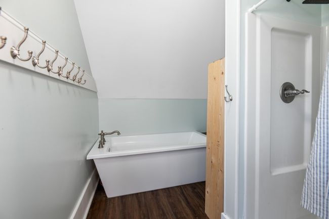Full bath featuring wood finished floors, a bathtub, baseboards, and a shower | Image 25