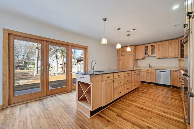 Kitchen featuring stainless steel dishwasher, open shelves, light brown cabinets, and a sink | Image 5