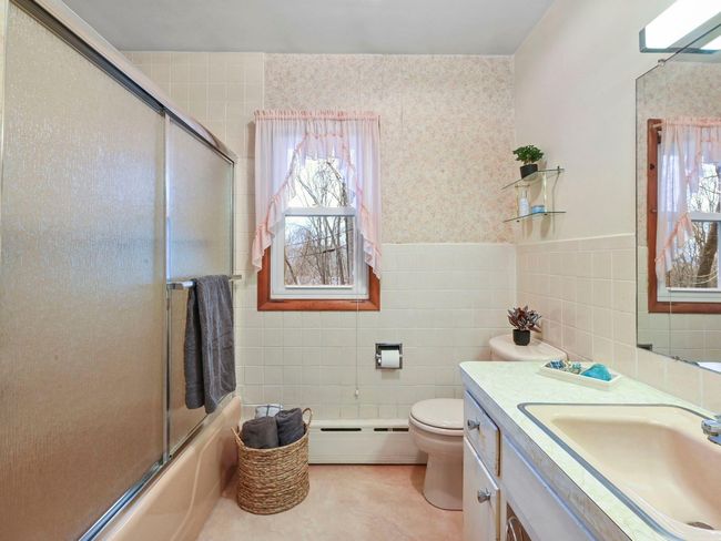 Full bathroom with vanity, a baseboard heating unit, tile patterned floors, toilet, and tile walls | Image 28