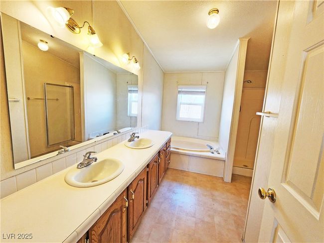 Full bathroom with tile patterned floors, a shower with shower door, a bath, and a sink | Image 24