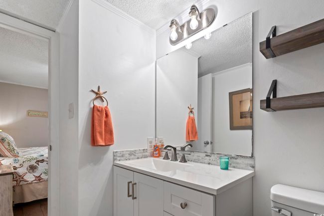 Ensuite bathroom with vanity, toilet, a textured ceiling, backsplash, and connected bathroom | Image 11