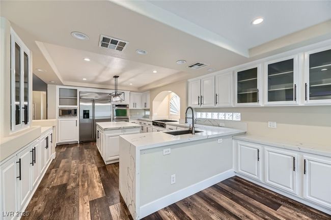 Kitchen featuring a tray ceiling, built in appliances, glass insert cabinets, white cabinets, and recessed lighting | Image 12