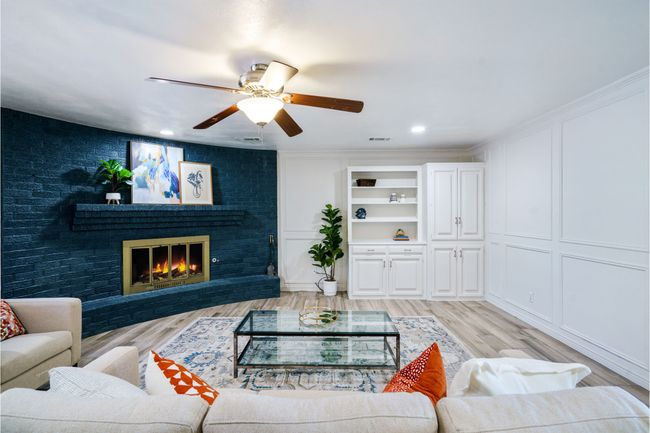Living area featuring a decorative wall, light wood-style flooring, ceiling fan, a brick fireplace, and recessed lighting | Image 9