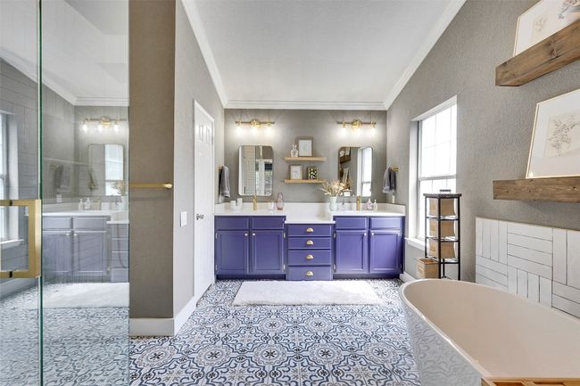Bathroom with ornamental molding, a soaking tub, double vanity, a shower with door, and baseboards | Image 23