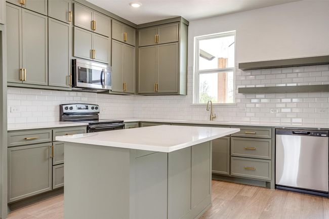 Kitchen with light wood-style floors, gray cabinets, light countertops, and appliances with stainless steel finishes | Image 12