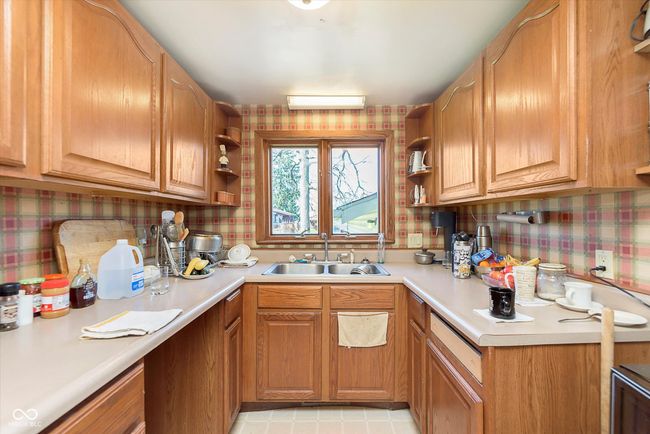kitchen with wallpapered walls, light countertops, backsplash, open shelves, and a sink | Image 13