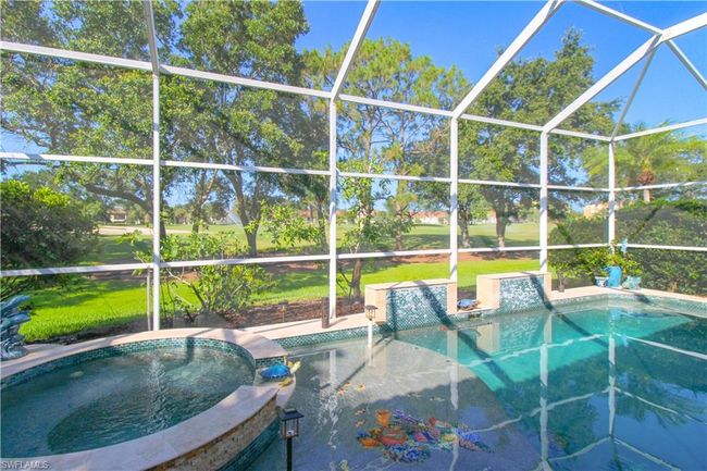 View of swimming pool featuring glass enclosure, an in ground hot tub, area for grilling, and a lawn | Image 11