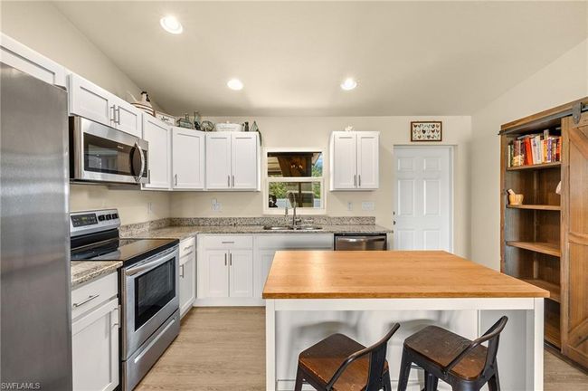 Kitchen with light wood finished floors, white cabinets, a sink, and stainless steel appliances | Image 7