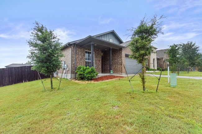 View of front of property featuring a garage, brick siding, concrete driveway, and board and batten siding | Image 4
