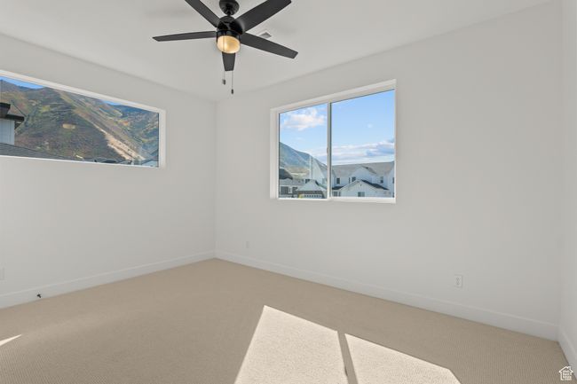 Carpeted empty room featuring a mountain view and a ceiling fan | Image 36