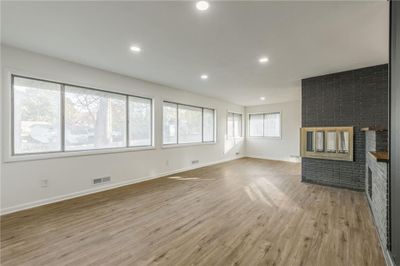 Unfurnished living room with light hardwood / wood-style floors and a brick fireplace | Image 3