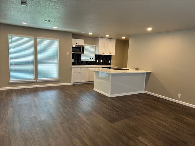 Kitchen featuring stainless steel microwave, baseboards, dark wood-style floors, white cabinetry, and light countertops | Image 22