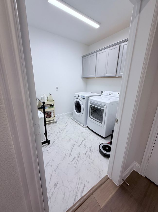 Laundry room with washer and dryer, cabinet space, and dark marble finish flooring and plumbed for additional sink | Image 8