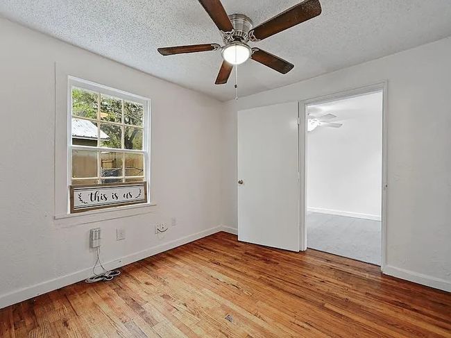 Empty room with hardwood / wood-style floors, ceiling fan, and a textured ceiling | Image 6
