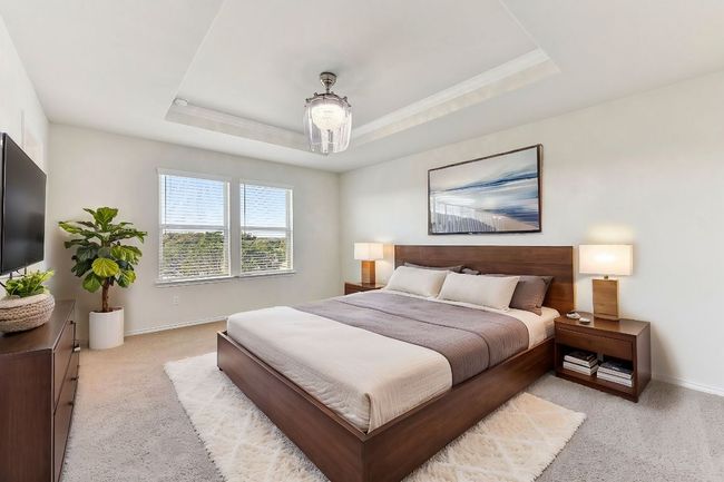 Bedroom featuring baseboards, light colored carpet, ornamental molding, and a raised ceiling | Image 22