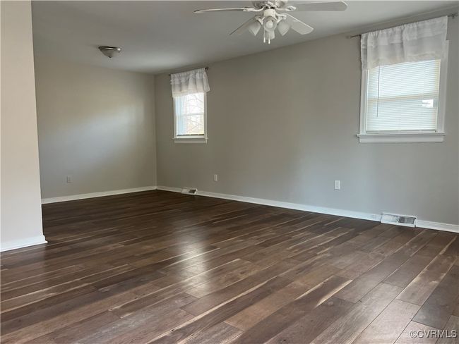 Unfurnished room with ceiling fan, wood finished floors, visible vents, and baseboards | Image 5