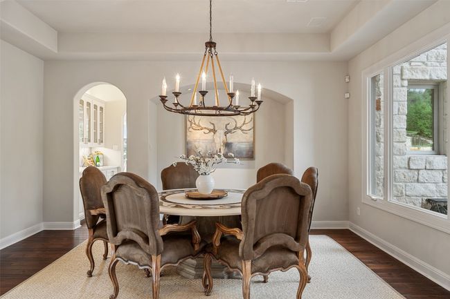 Dining area featuring a chandelier, arched walkways, dark wood finished floors, and baseboards | Image 7