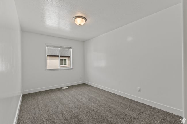 Empty room featuring dark colored carpet, a textured ceiling, and baseboards | Image 11