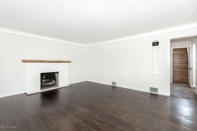 Unfurnished living room featuring a brick fireplace and dark wood-type flooring | Image 10