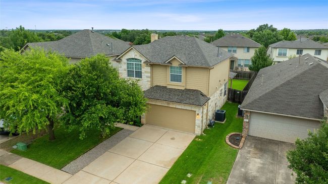 Traditional-style house featuring stone siding, concrete driveway, a chimney, and a shingled roof | Image 40