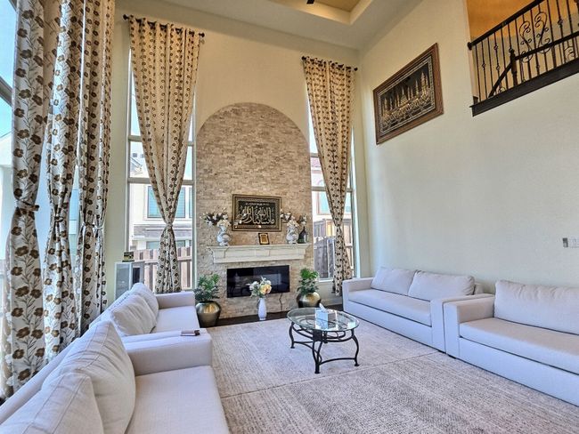 Living room with healthy amount of natural light, a stone fireplace, and a towering ceiling | Image 5