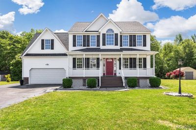 Colonial house with a front lawn, covered porch, and a garage | Image 1