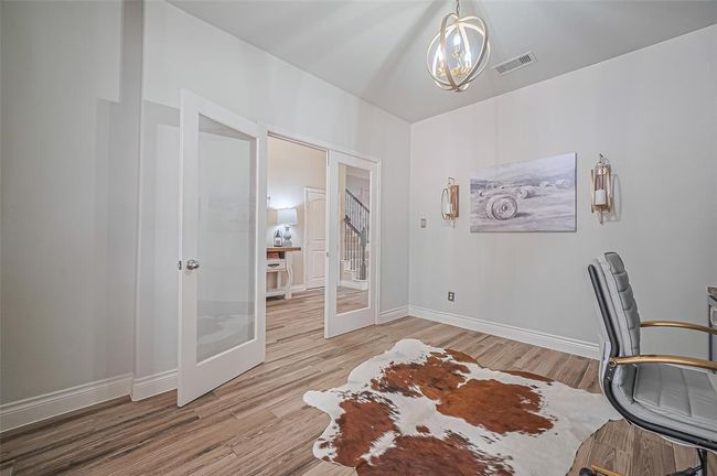 Enclosed by glass French doors, this beautifully appointed room is bathed in natural light and offers flexible functionality—ideal as a sophisticated home office, cozy sitting area, or personalized flex space. | Image 8