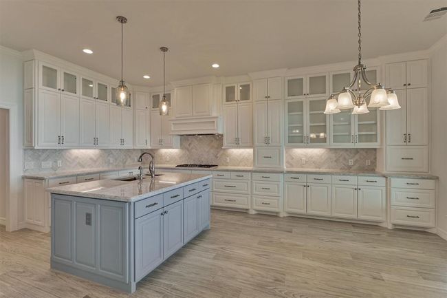 The cabinetry seamlessly extends into a serving-style buffet adjacent to the dining area, providing both convenience and elegance. This well-designed kitchen includes soft-close drawers and cabinets, two appliance garages to keep everyday items neatly tucked away, seeded glass cabinet doors, under-cabinet lighting, and solid wood panel cabinetry throughout the home—highlighting both quality craftsmanship and thoughtful design. | Image 14