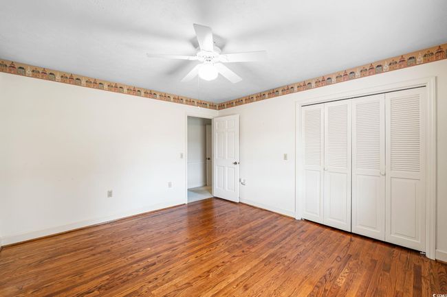 Unfurnished bedroom featuring wood finished floors, baseboards, a ceiling fan, and a closet | Image 26