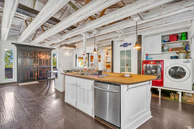 Kitchen featuring stainless steel dishwasher, butcher block countertops, white cabinets, dark wood-type flooring, and independent washer and dryer | Image 6