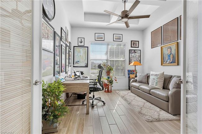 Office space with baseboards, a tray ceiling, ceiling fan, and wood tiled floor | Image 39