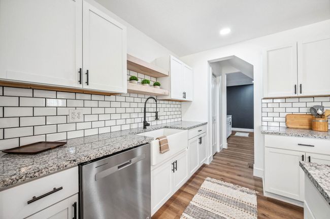Kitchen with tasteful backsplash, open shelves, dishwasher, a sink, and wood finished floors | Image 13