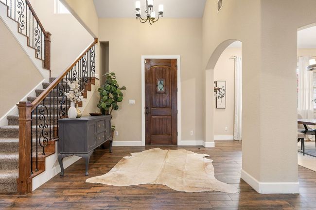 Warm and inviting entryway with tall ceilings and solid wood front door. | Image 5